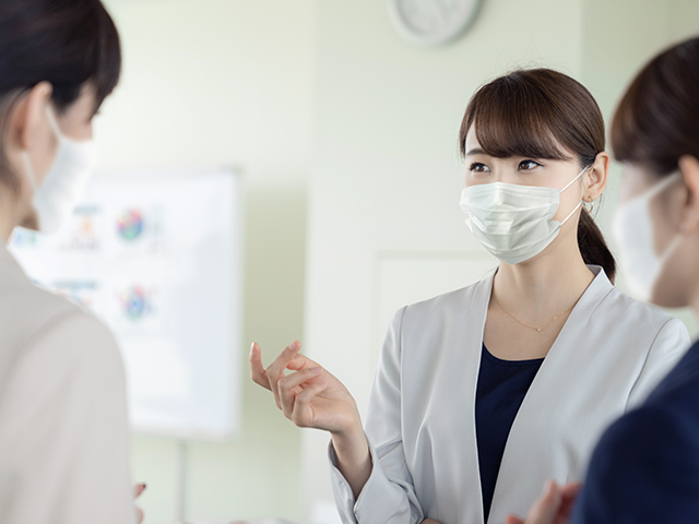 新しい生活様式にあわせてマスクを着用しながら会話をする社員のイメージ写真
